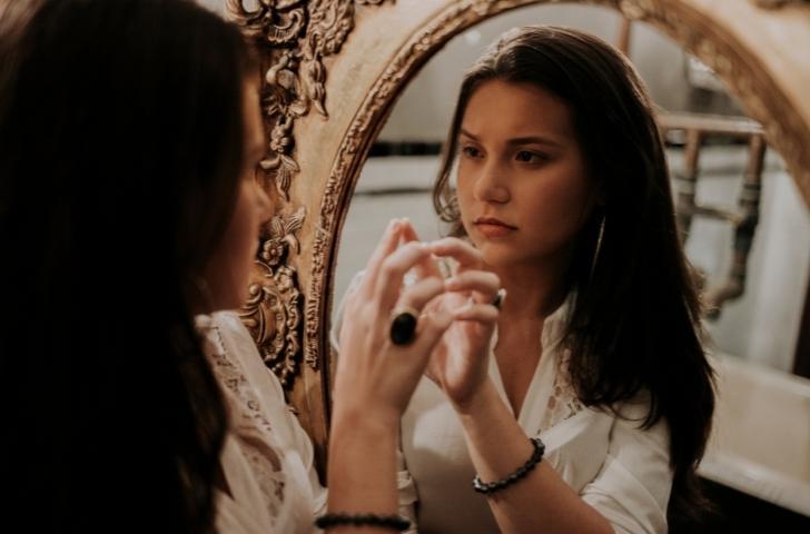 Mulher pensativa diante do espelho, refletindo sobre seus próprios desejos.